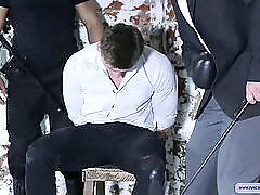 Muscular guy on his knees with arms tied back receiving flogging in an intense interrogation